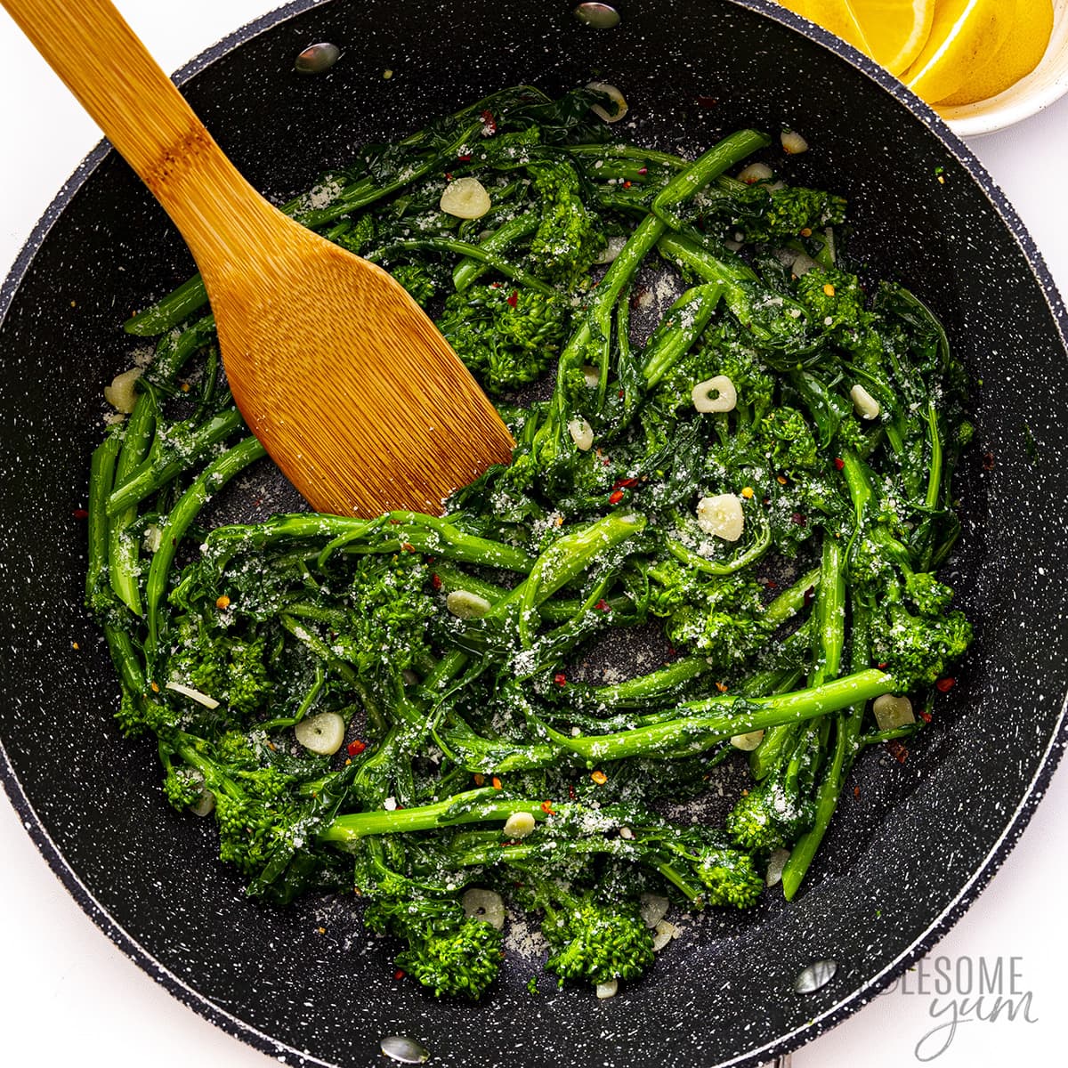 Sauteed broccoli rabe with parmesan and lemon wedges.