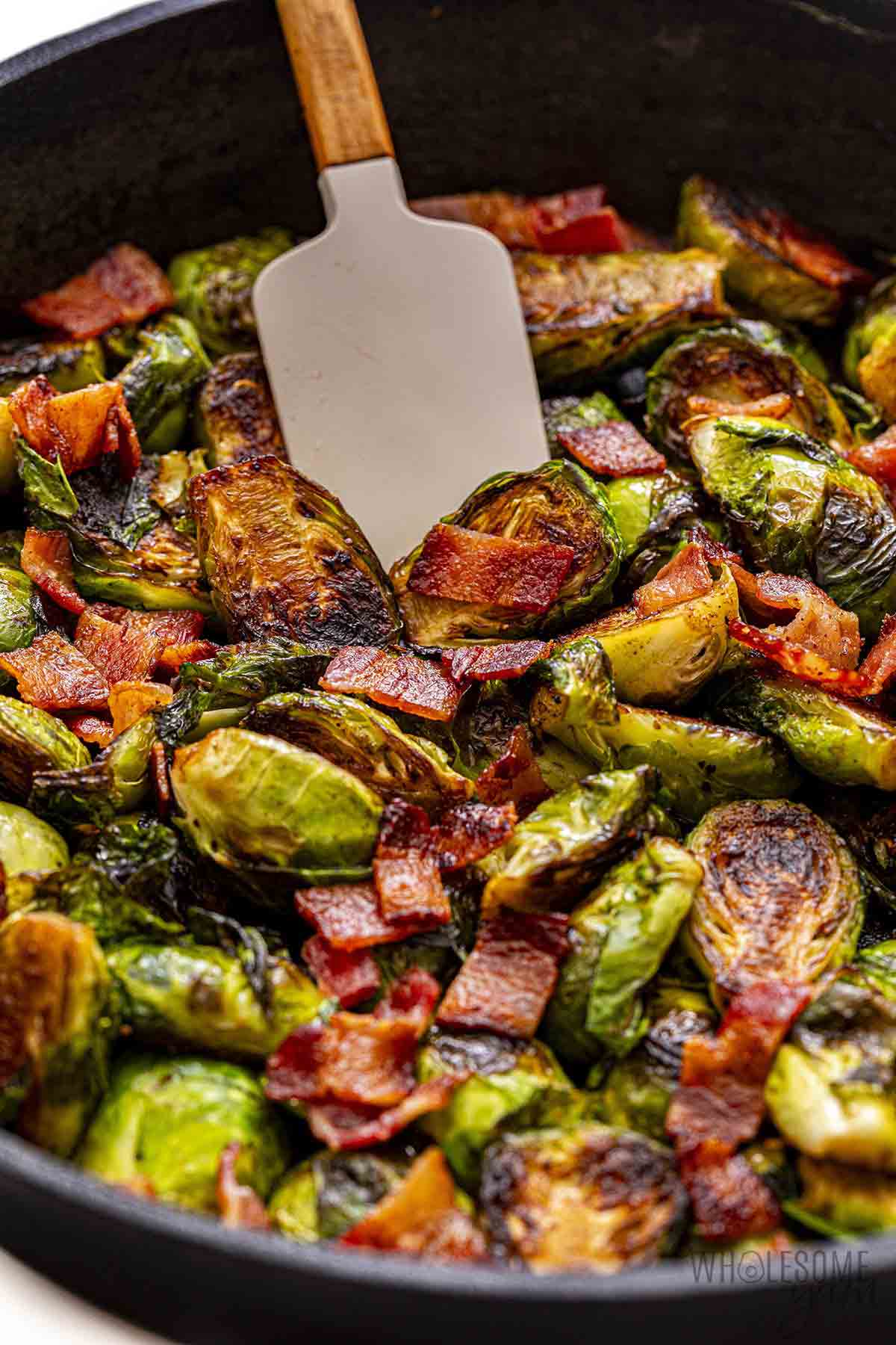 Fried brussels sprouts with bacon in a skillet.
