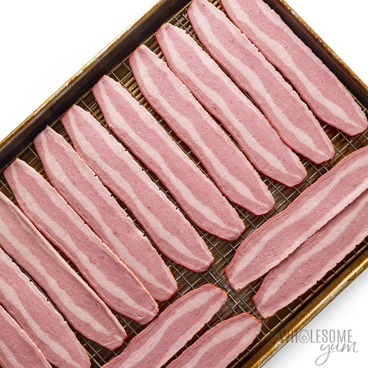 Raw turkey bacon slices arranged on a baking sheet.