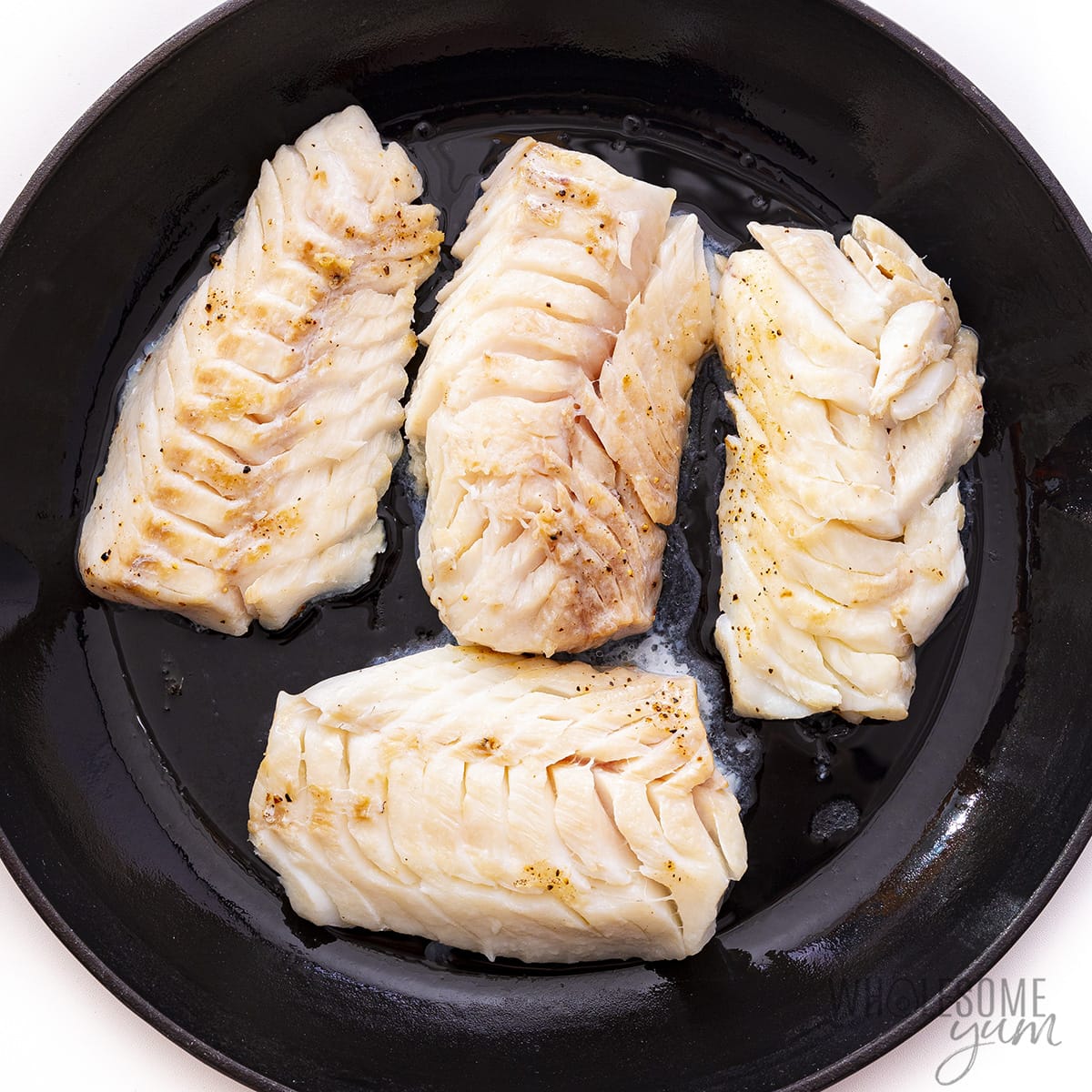 Seared cod in a pan.