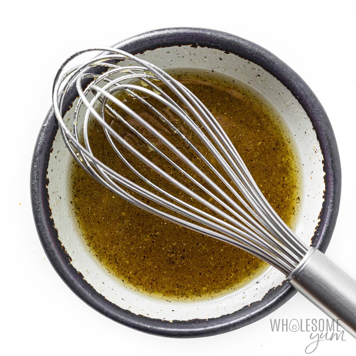 Dressing in a bowl with a whisk.