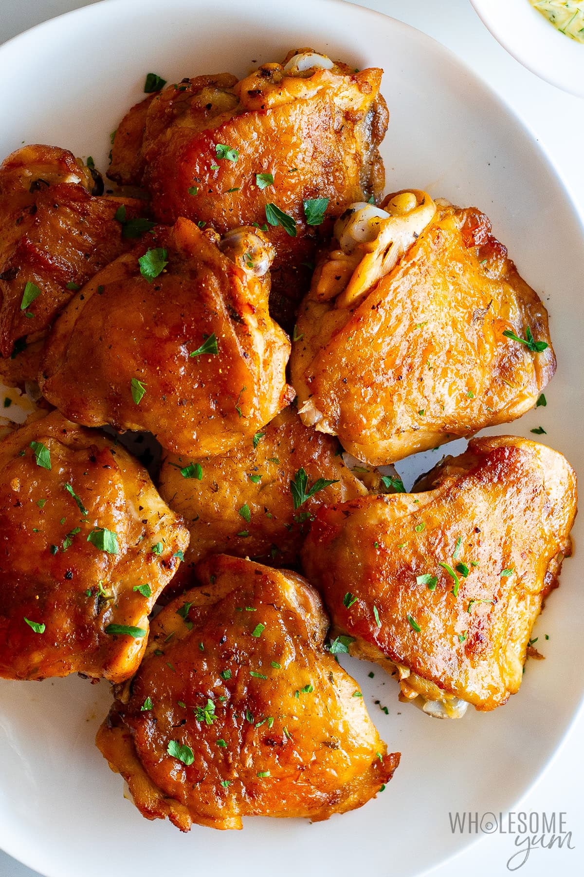 Baked chicken thighs on a platter garnished with fresh parsley.