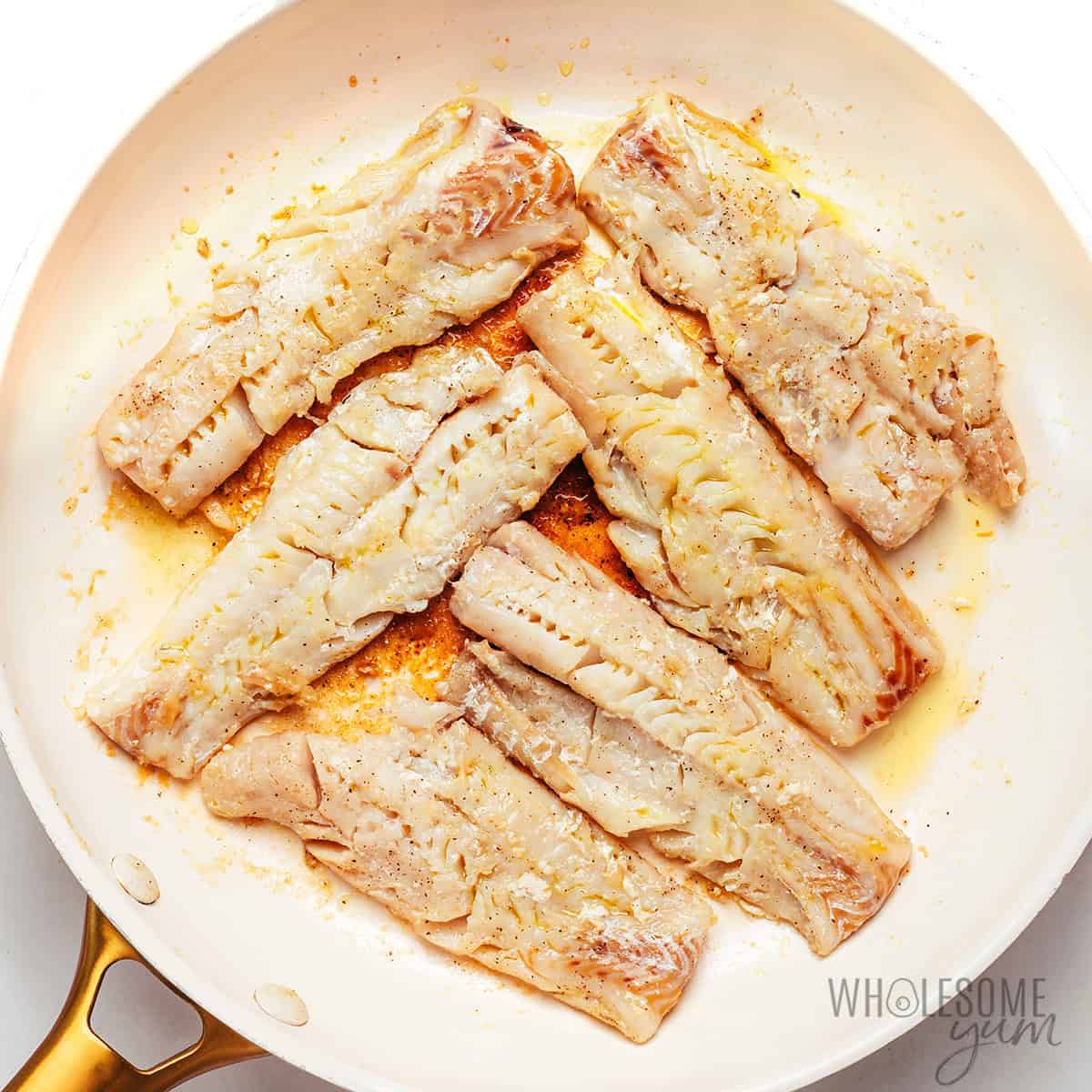 Pan frying cod fillets in a skillet.