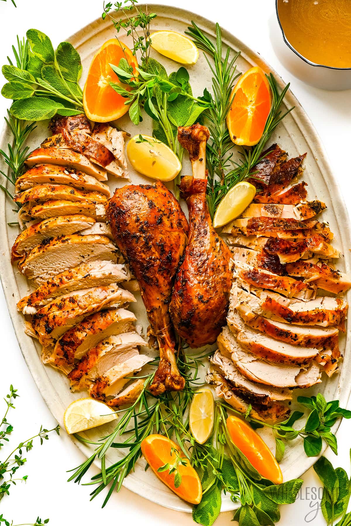 Sliced turkey next to turkey legs on a serving platter.