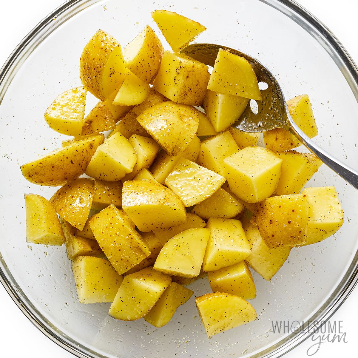 Cubed potatoes in a bowl with seasonings.