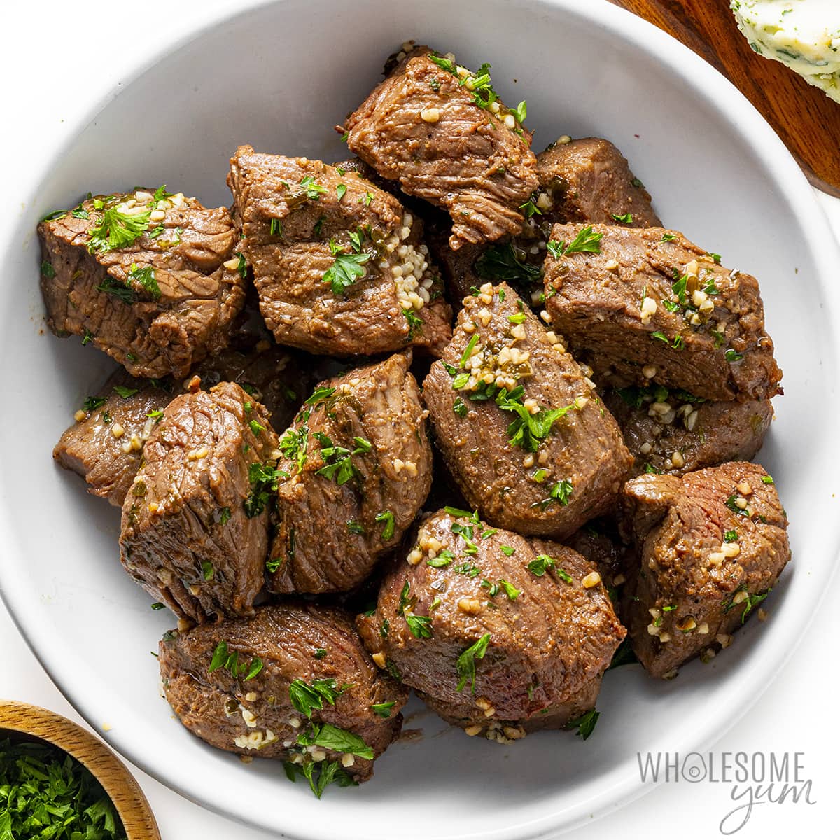Air fryer steak bites in a bowl garnished with parsley.