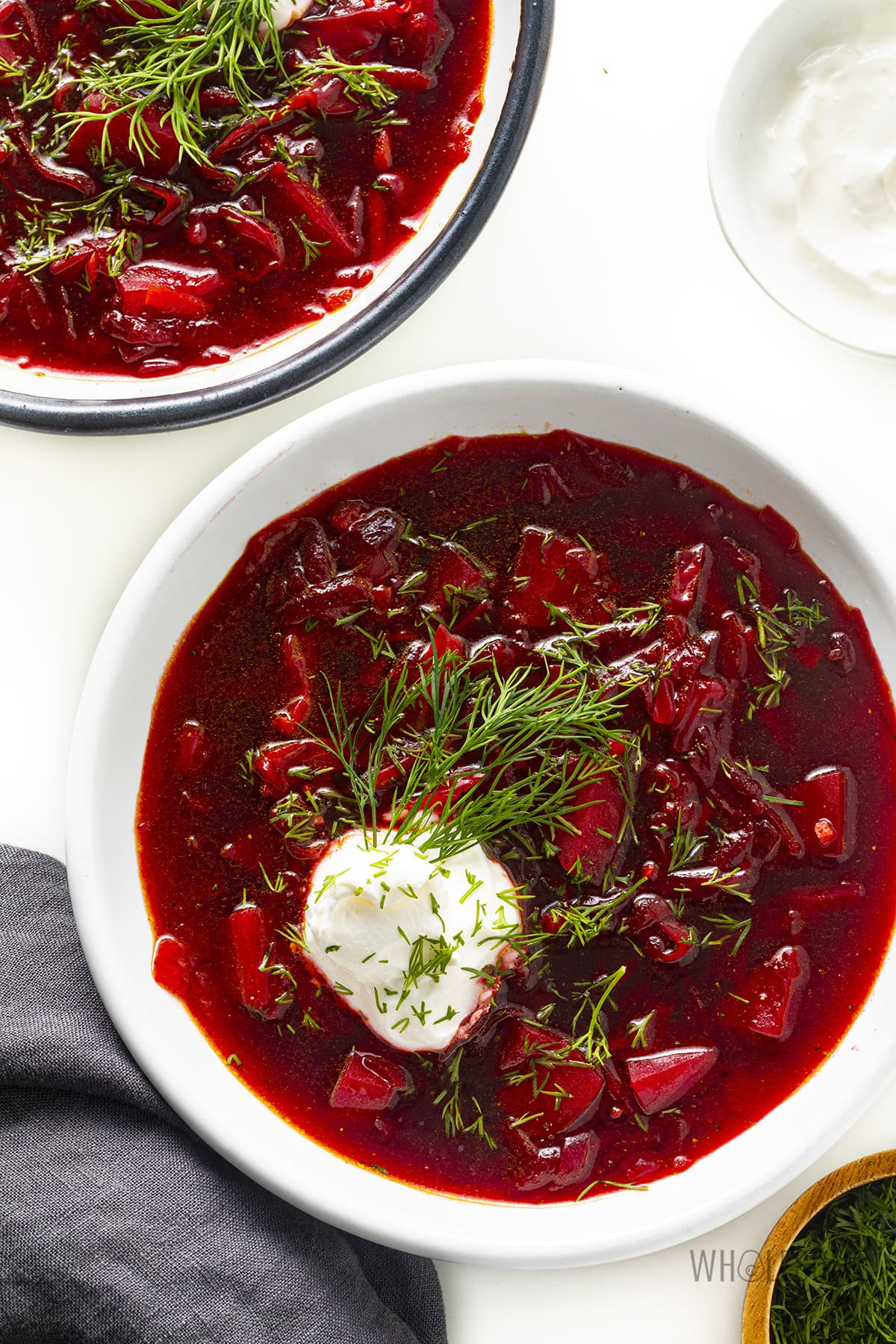 Beet soup in bowls with garnishes.