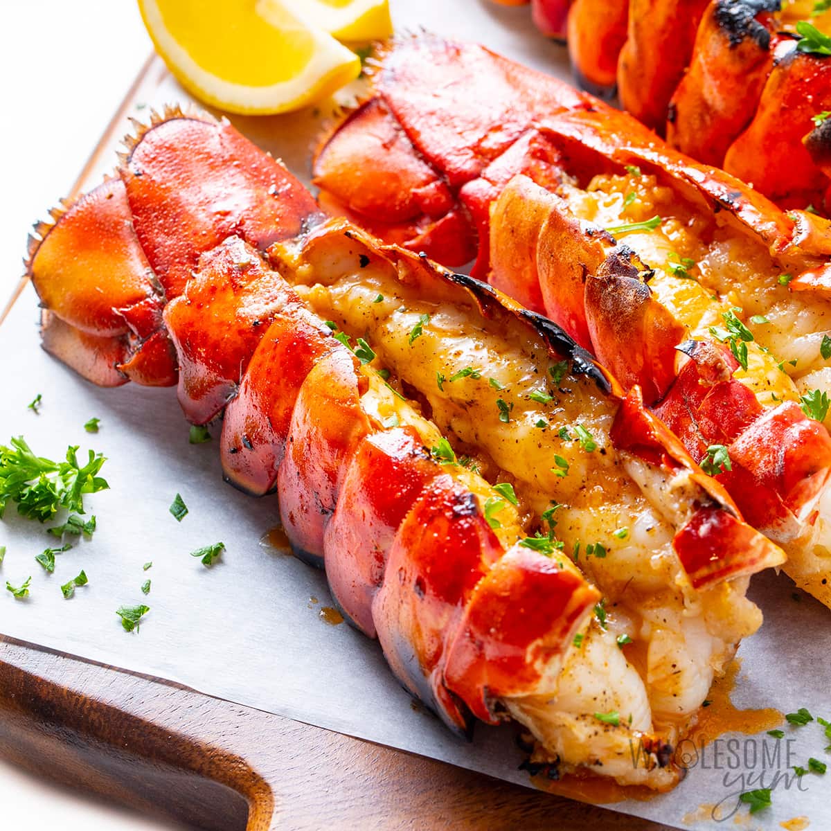 Grilled lobster tail garnished with fresh parsley and lemon wedges.