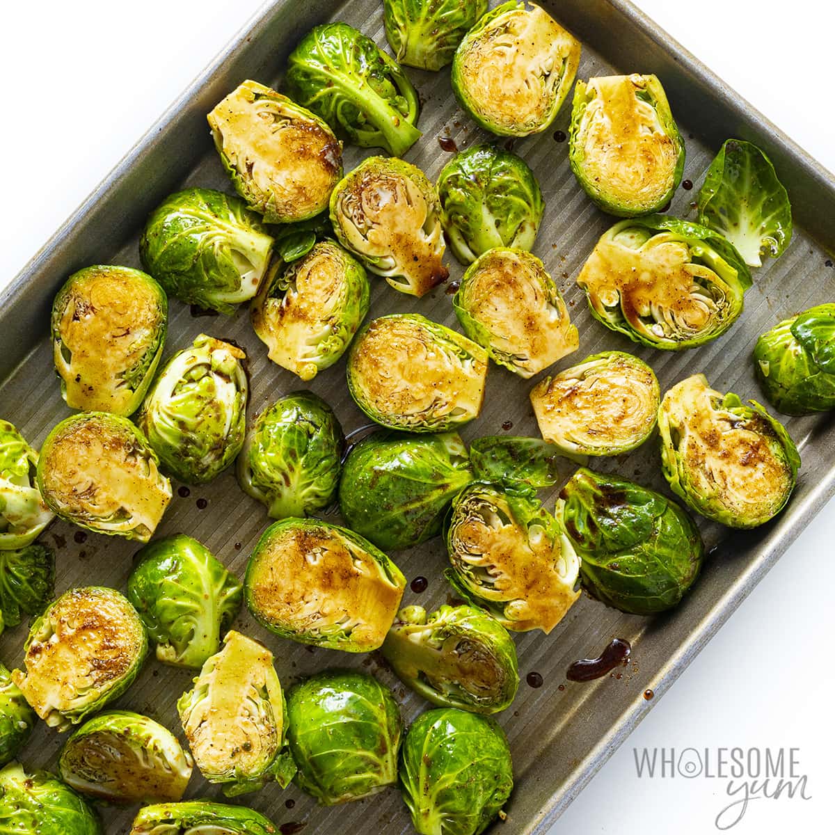 Raw brussels sprouts arranged in a single layer on a baking sheet.