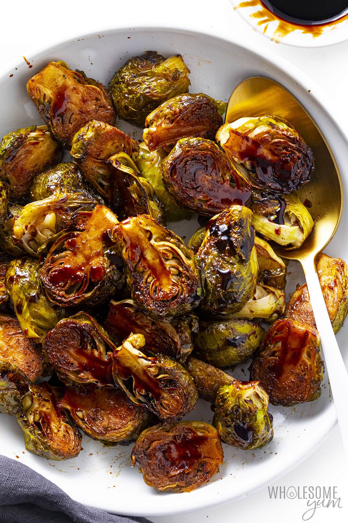 Brussels sprouts with balsamic glaze in a bowl with serving spoon.