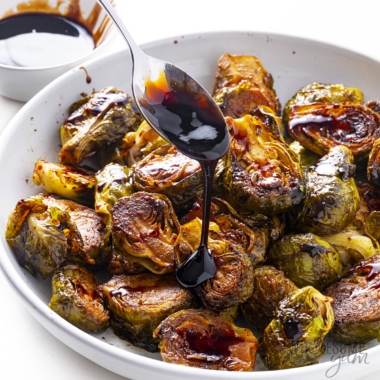 Balsamic brussels sprouts drizzled with balsamic glaze from a spoon.