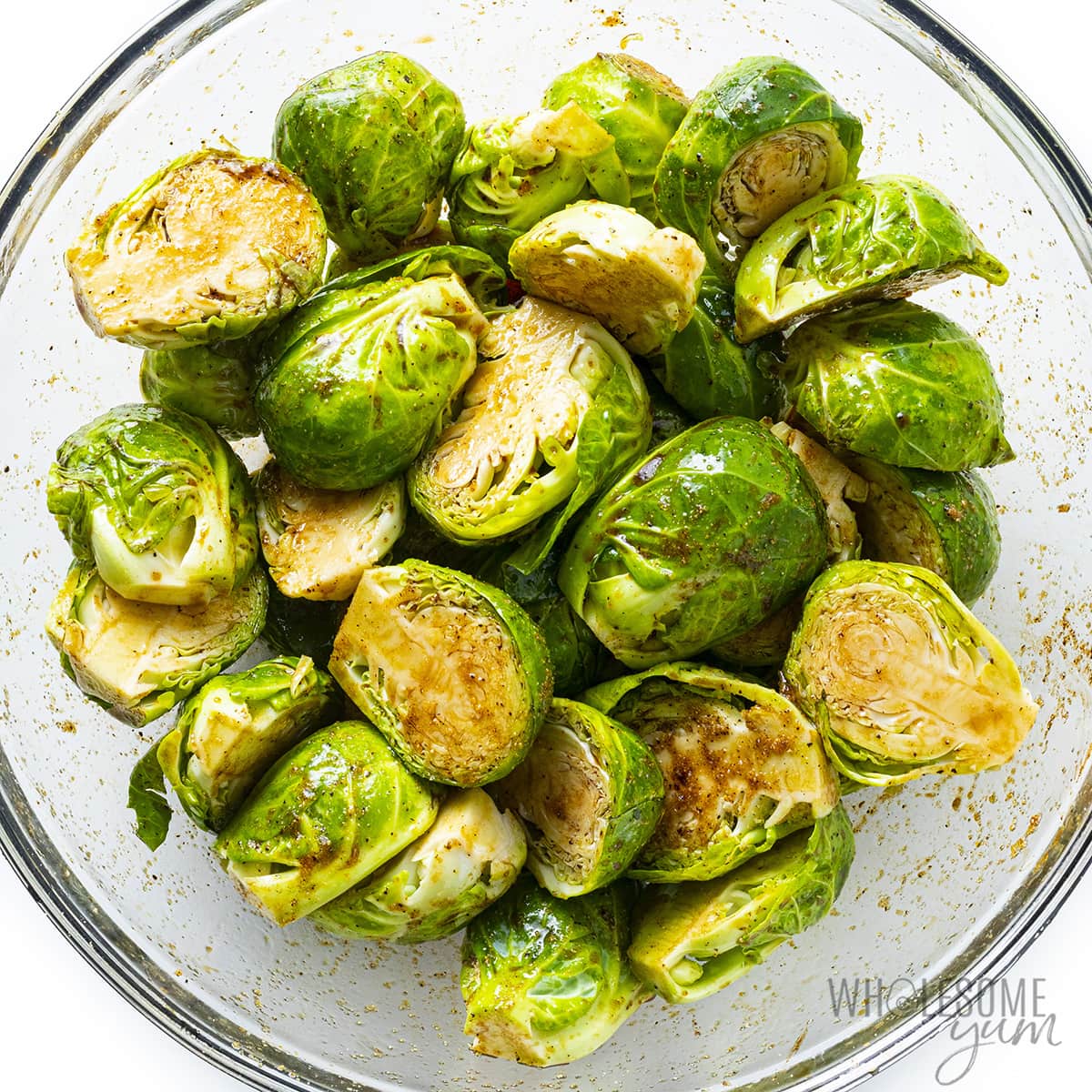 Halved brussels sprouts, seasoned in a bowl.