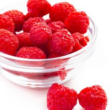 Raspberries in bowl on white background.