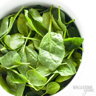 Spinach in a bowl on white background.