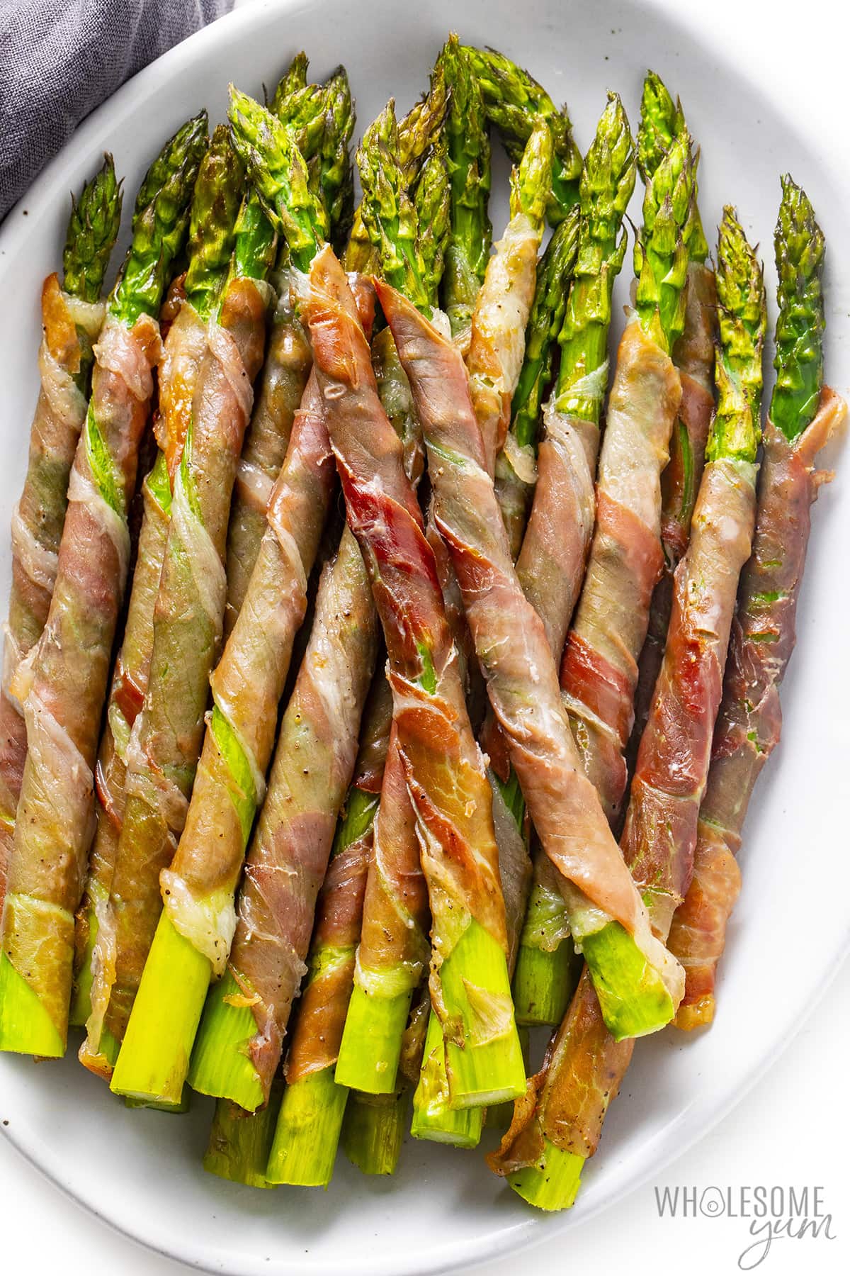 Prosciutto wrapped asparagus spears on a platter.