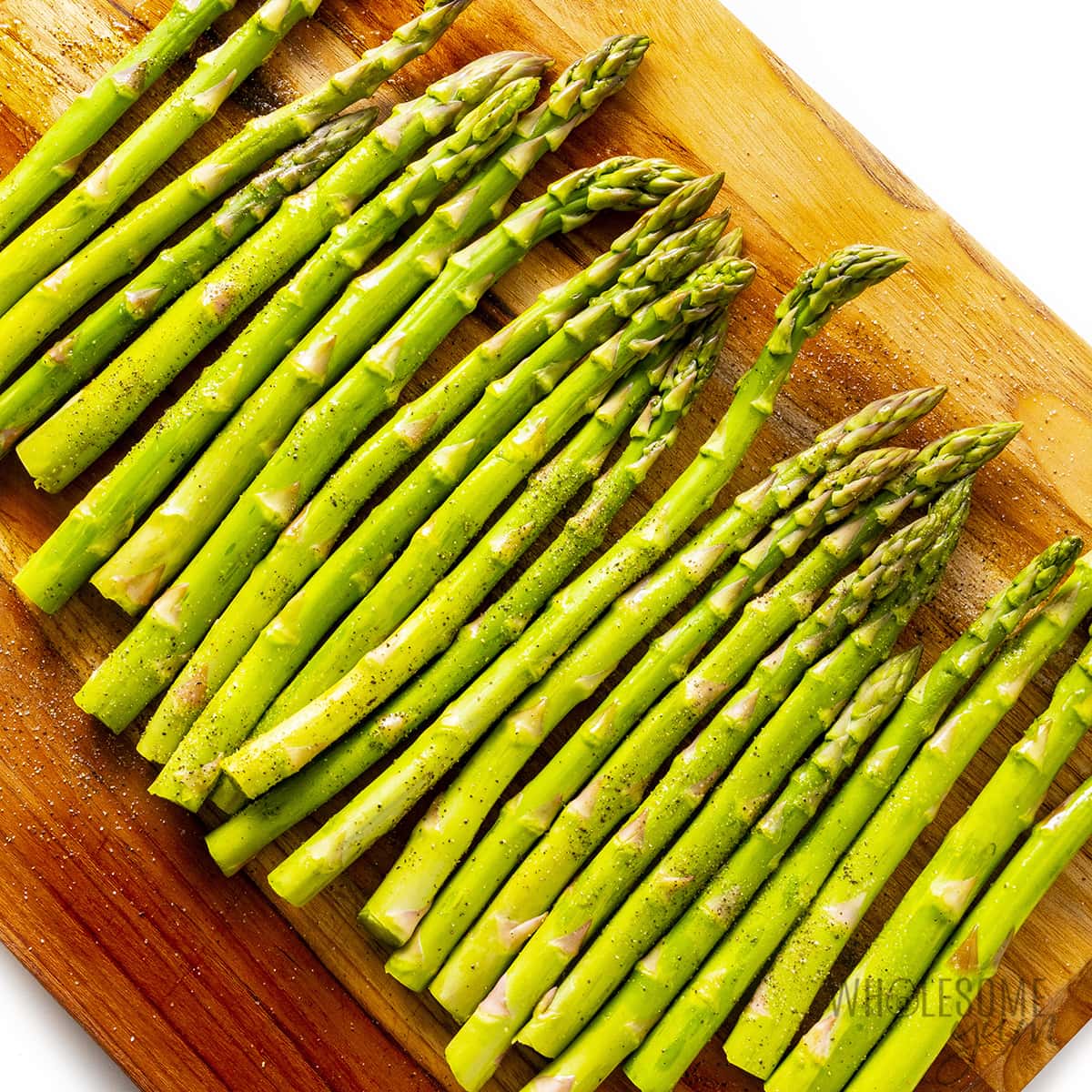 Asparagus prepped and seasoned on a cutting board.