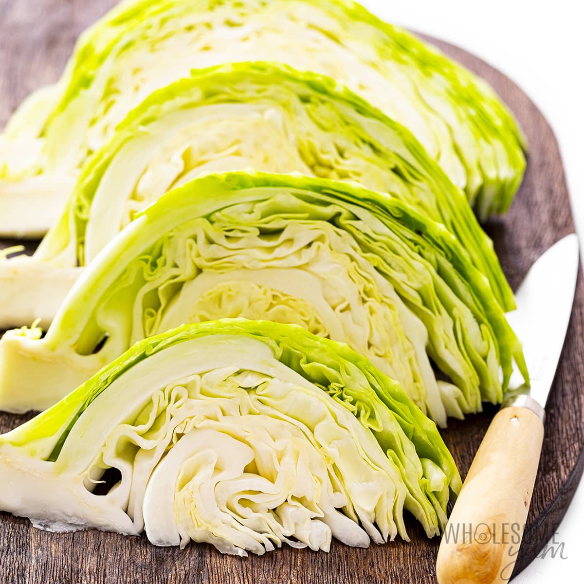 Cabbage cut into wedges on a cutting board.