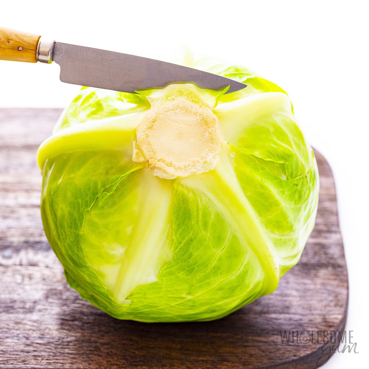 Head of cabbage being cut with a knife.