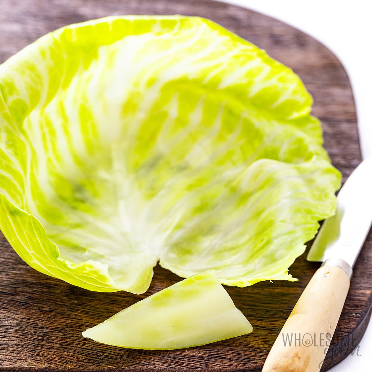 Cabbage leaf on the cutting board with core cut away.