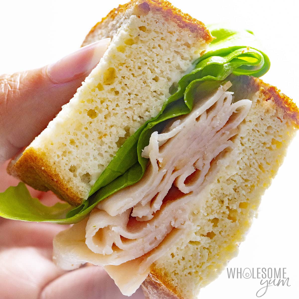 Holding a keto sandwich with turkey, lettuce, and mayo.