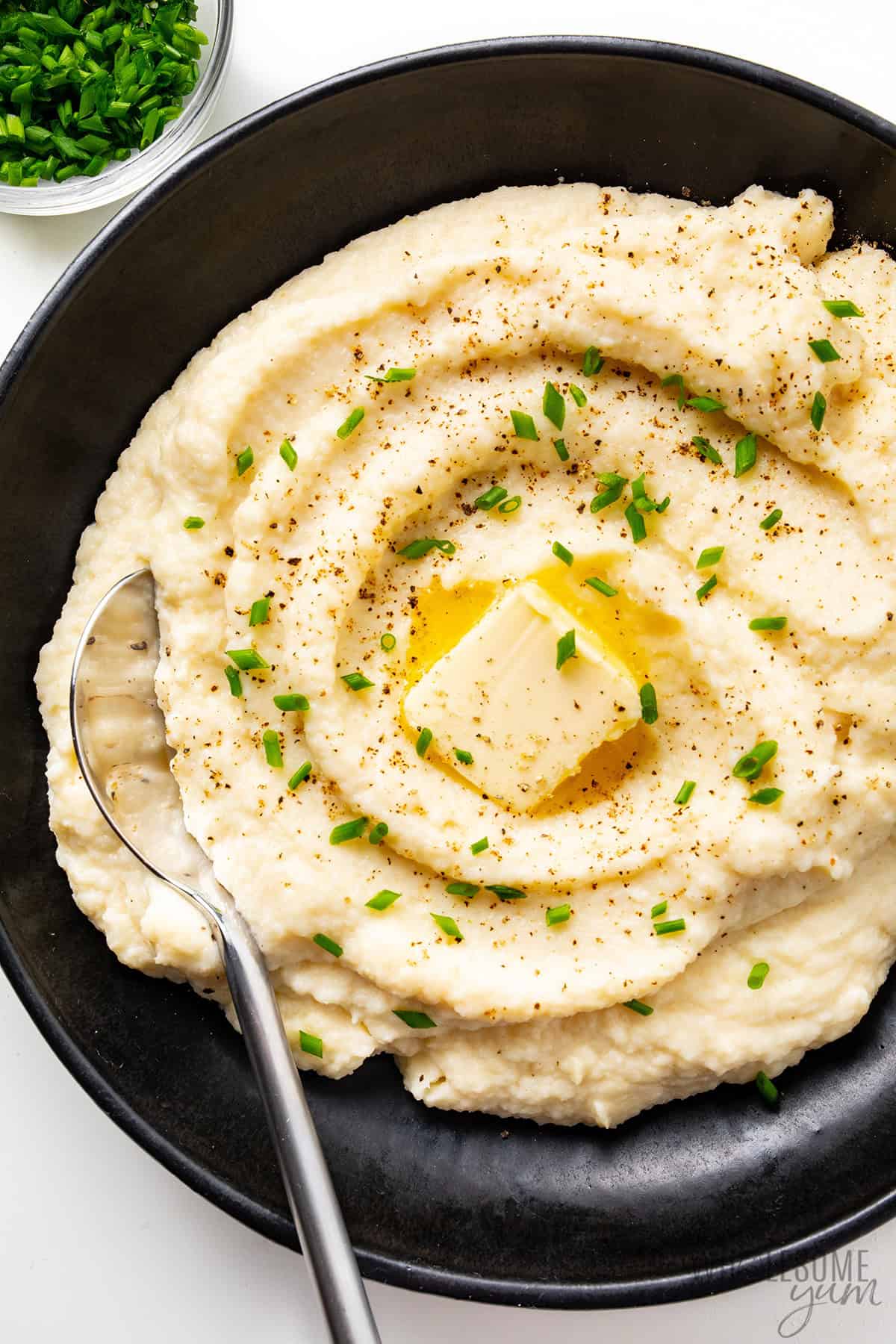 Cauliflower mashed potatoes served in a bowl with butter and chives.