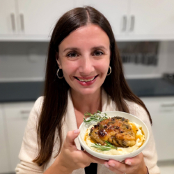 Maya holding a bowl of mashed cauliflower with chicken on top.
