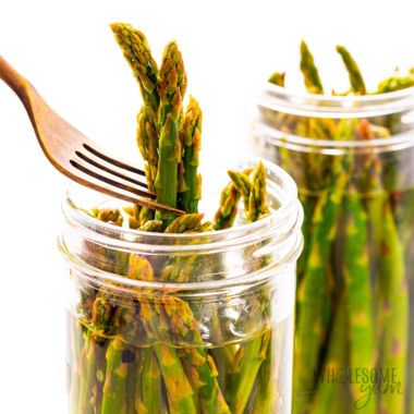 Pickled asparagus pulled out of a jar with a fork.