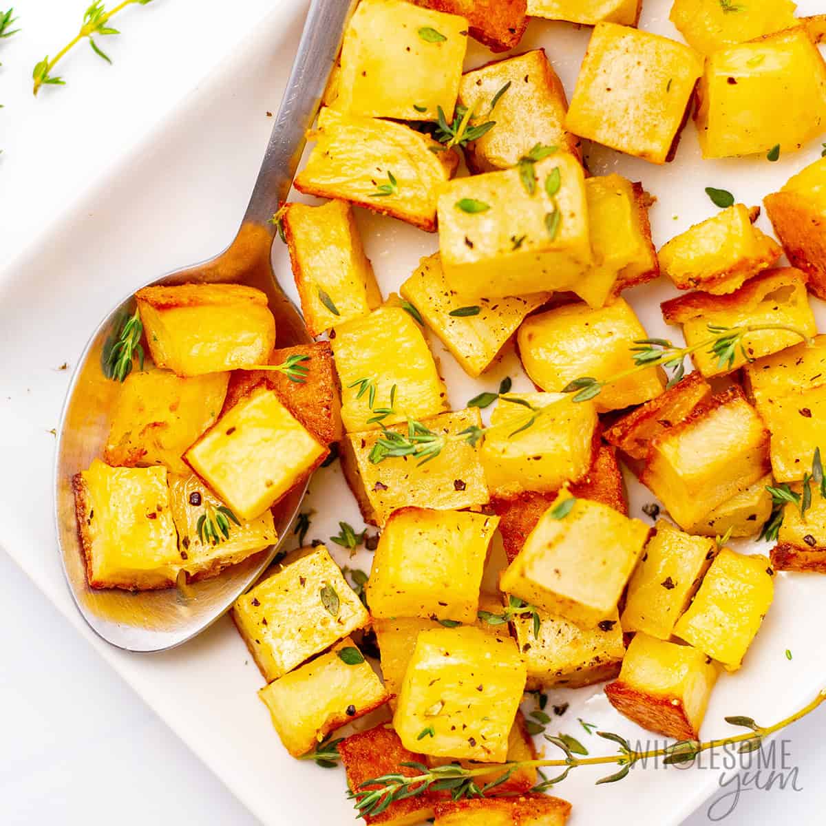 Roasted rutabaga recipe on a platter with a spoon.