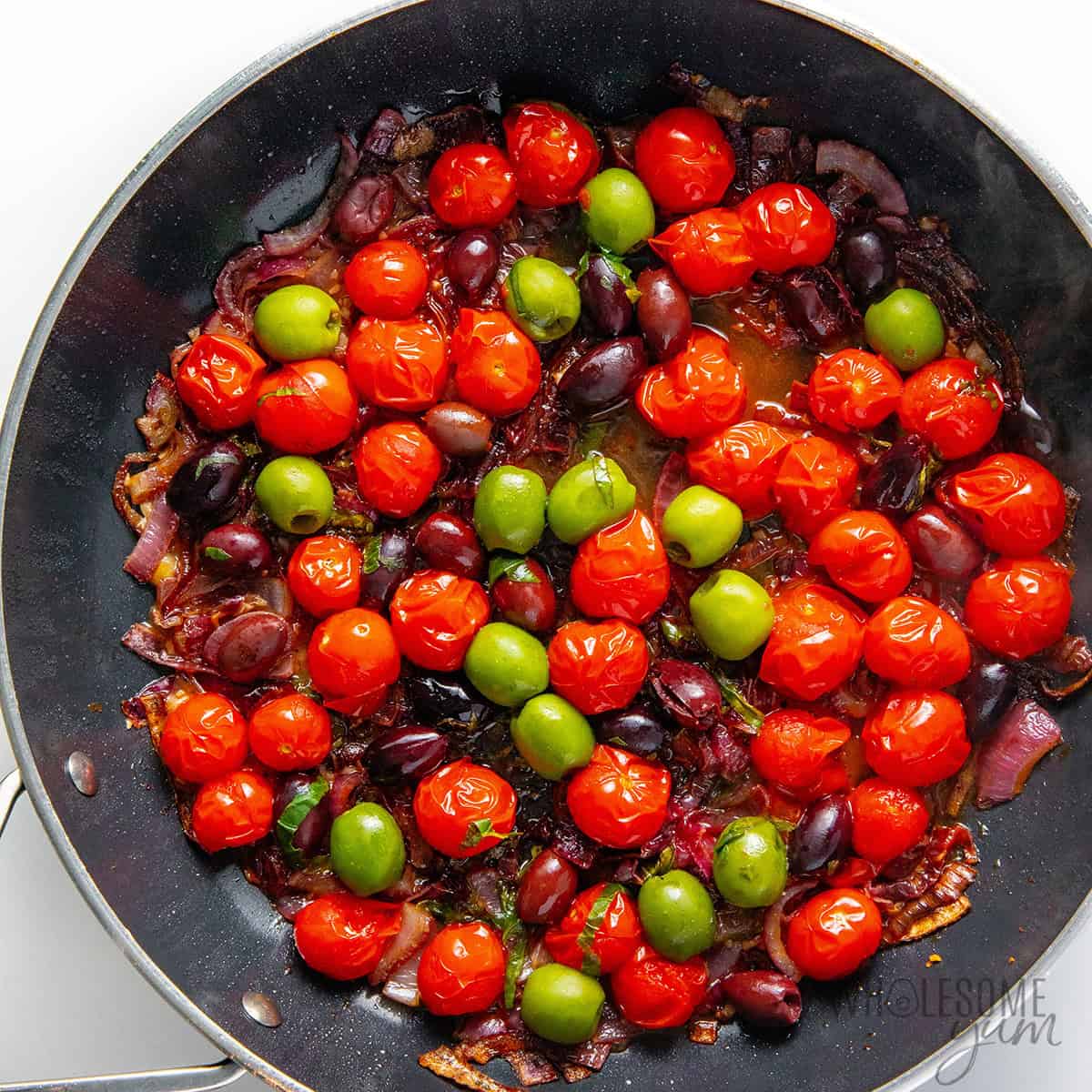 Cookiing tomatoes and olives in the skillet.