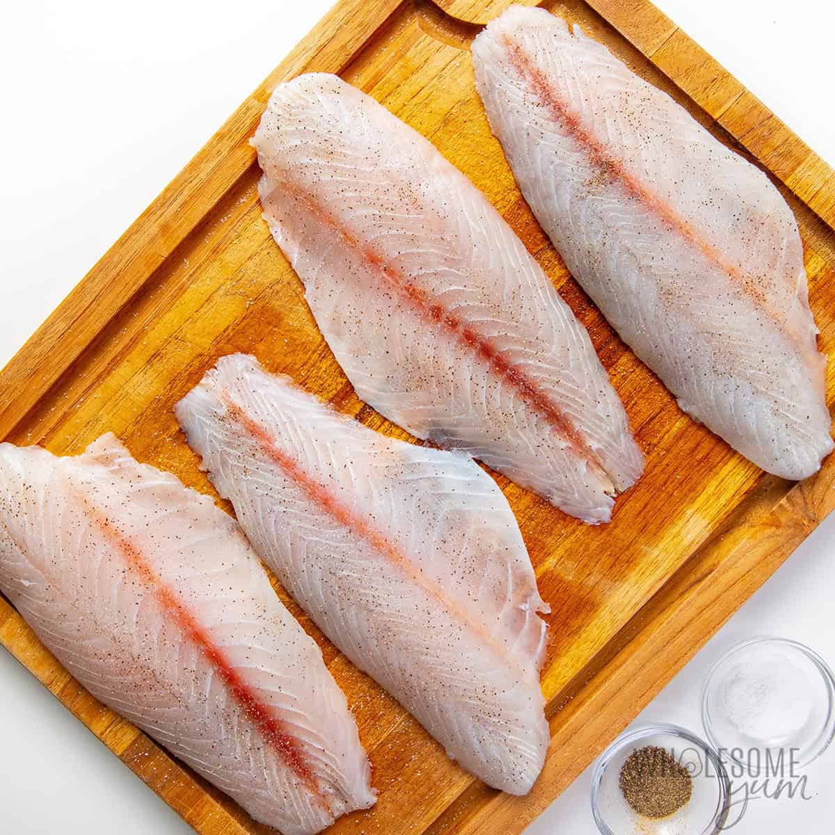 Seasoned barramundi on a cutting board.