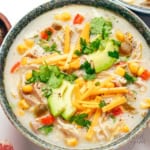 Chicken corn soup in a bowl with toppings.