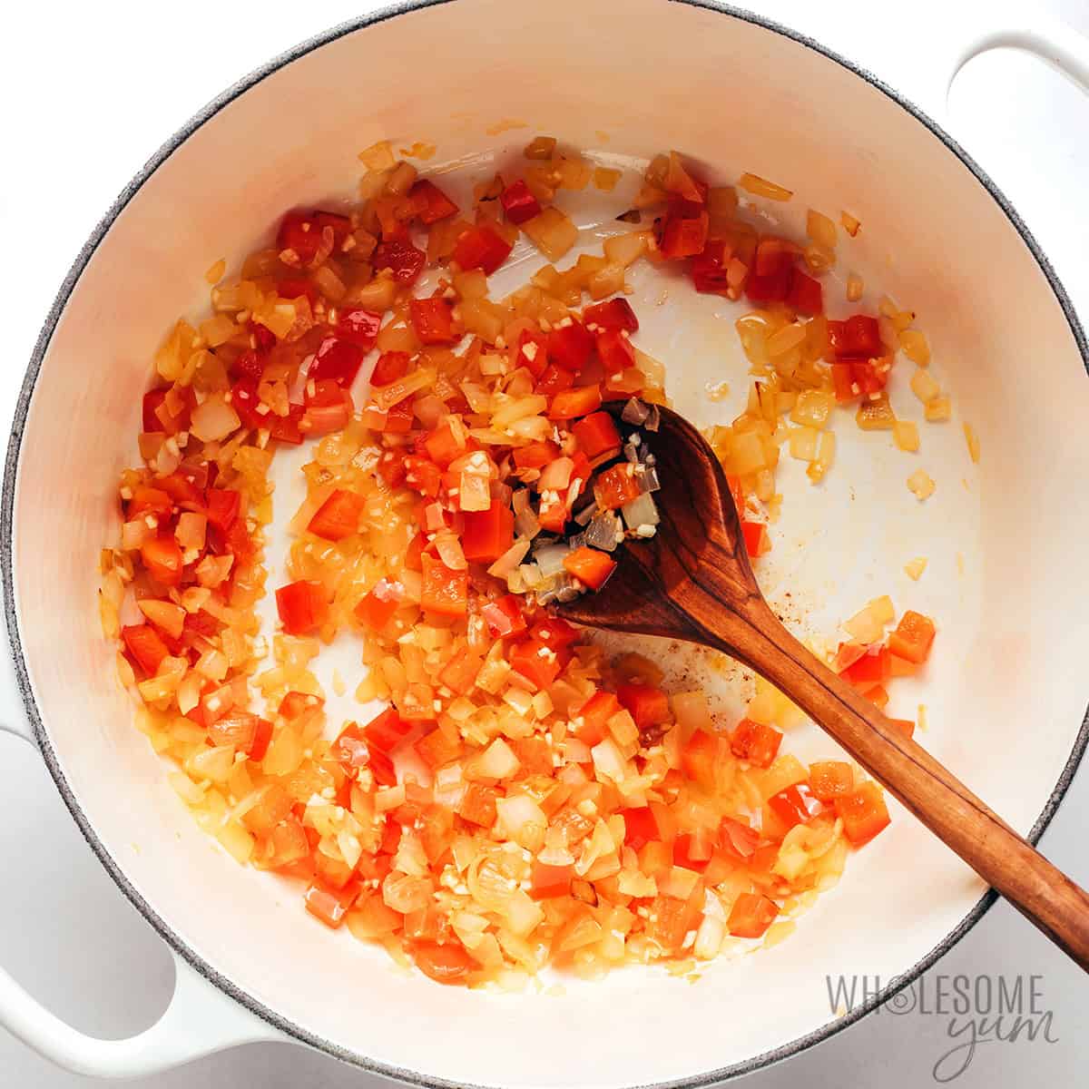 Sauteeing bell peppers and aromatics in a Dutch oven.