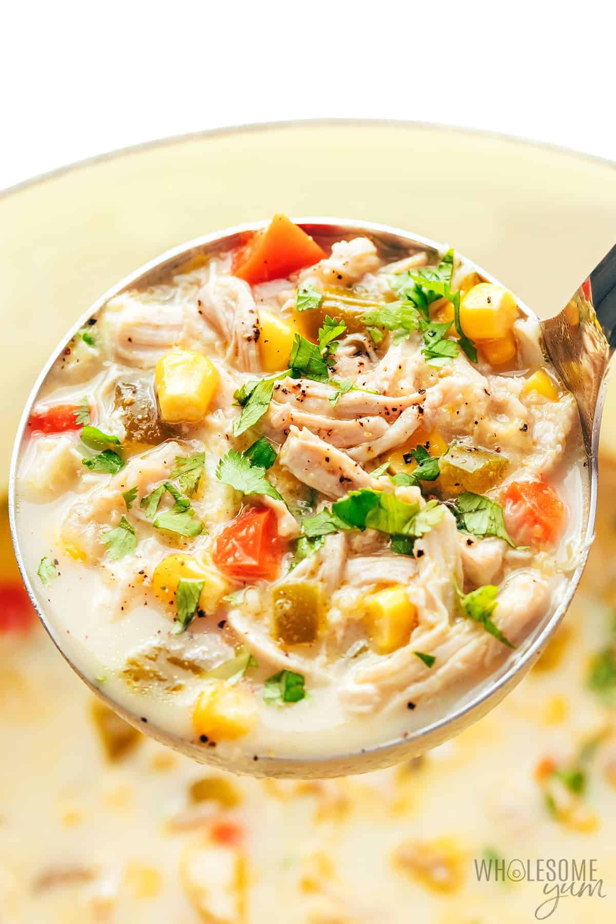Rich, creamy chicken corn soup in a ladle up close.