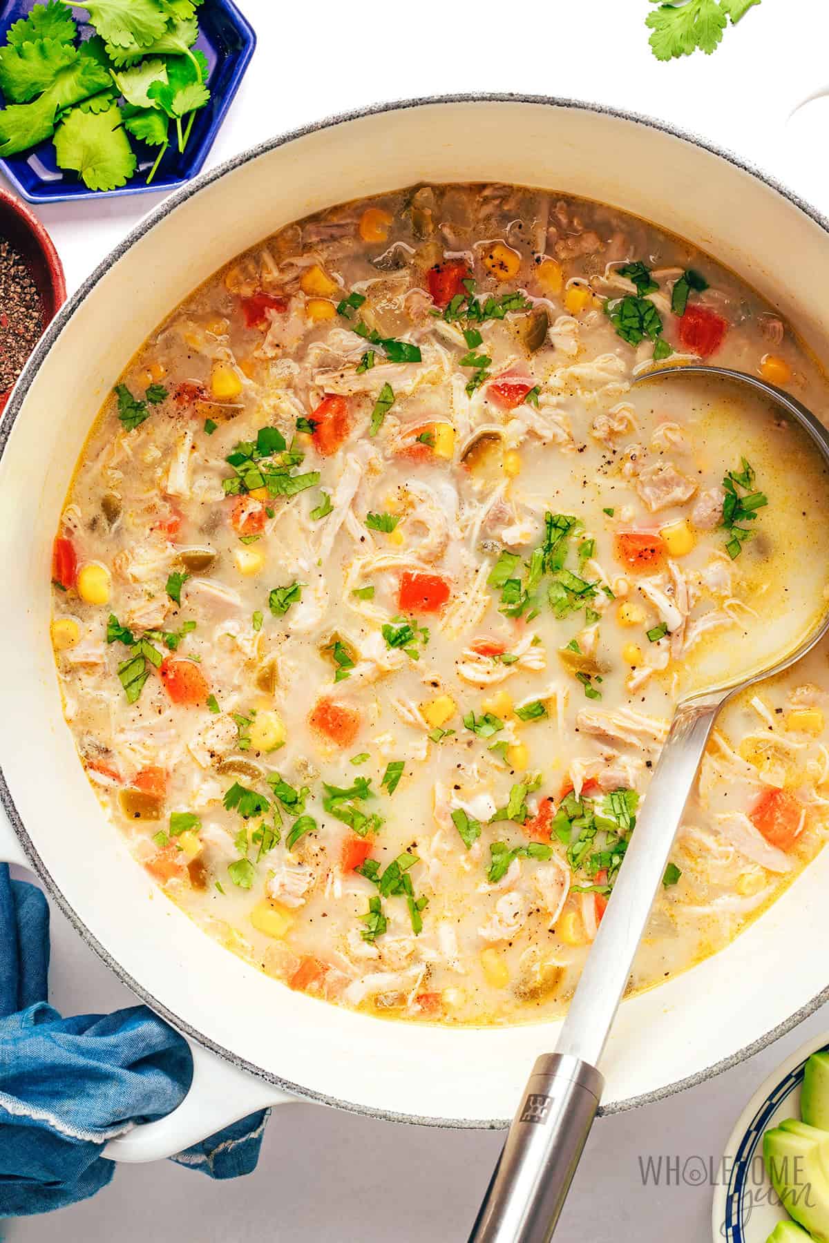 Fully cooked chicken corn soup recipe garnished with fresh cilantro, and avocado on the side.