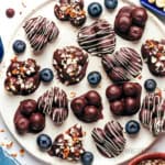 Chocolate covered blueberries on a plate.