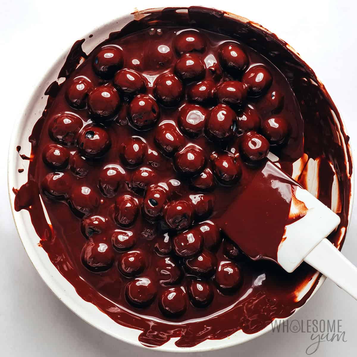 Coating blueberries in melted chocolate.