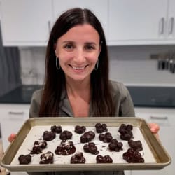 Maya holding a sheet pan of chocolate covered strawberries.