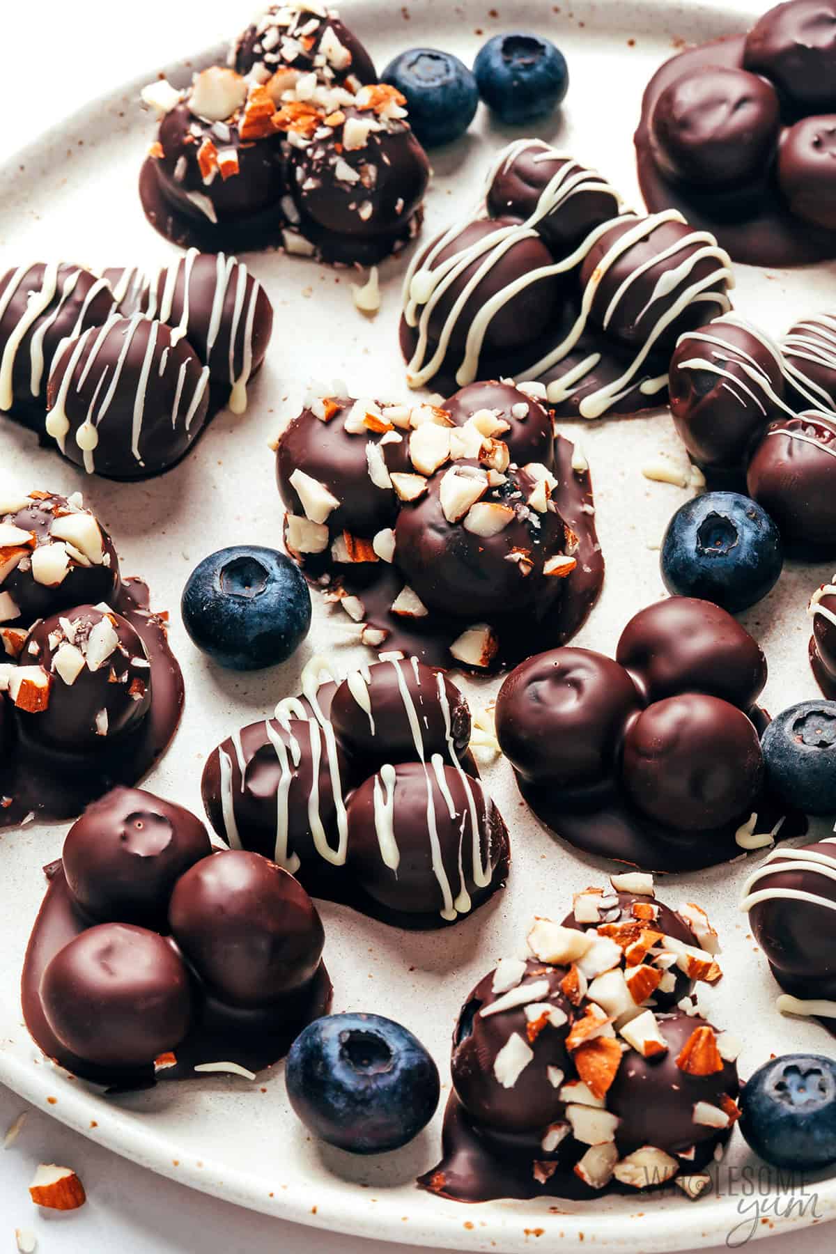 Shiny decorated chocolate covered blueberries on a plate.