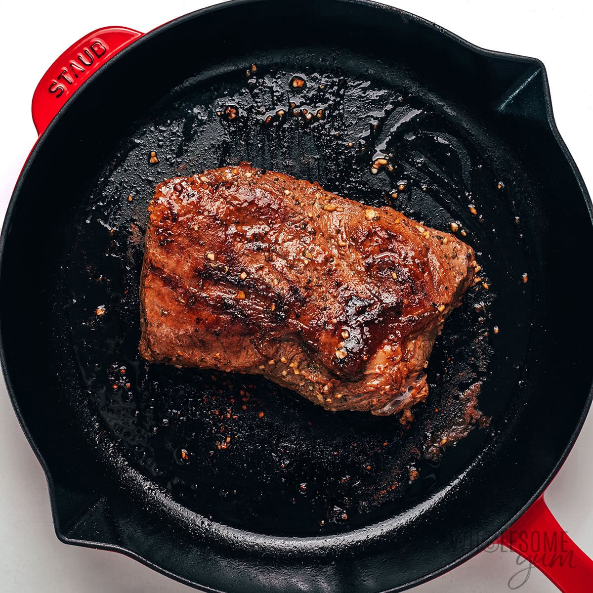 Searing steak in a cast iron skillet.