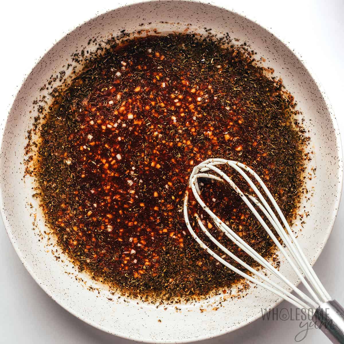 Whisking flat iron steak marinade in a bowl.