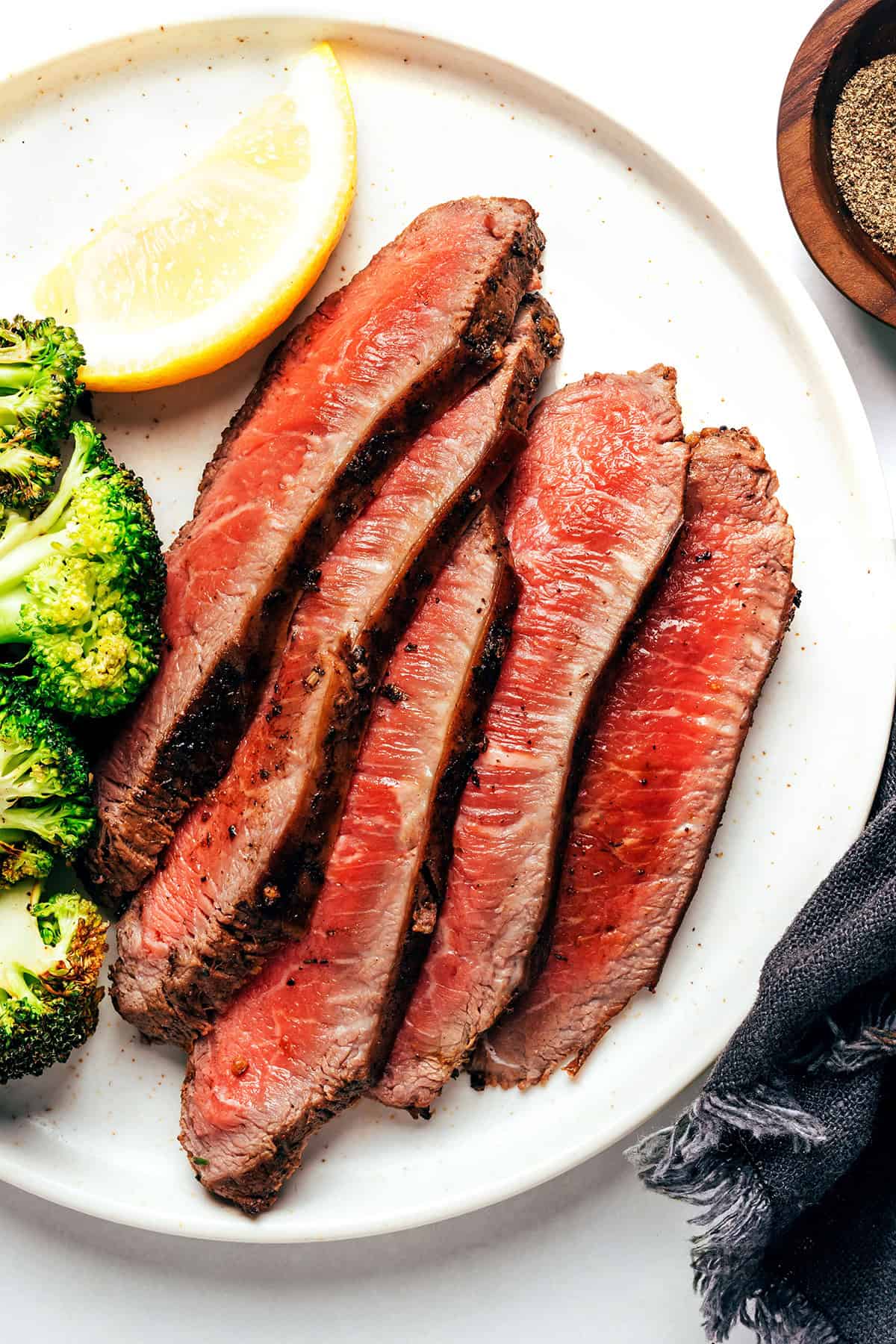 Sliced steak plated with broccoli.