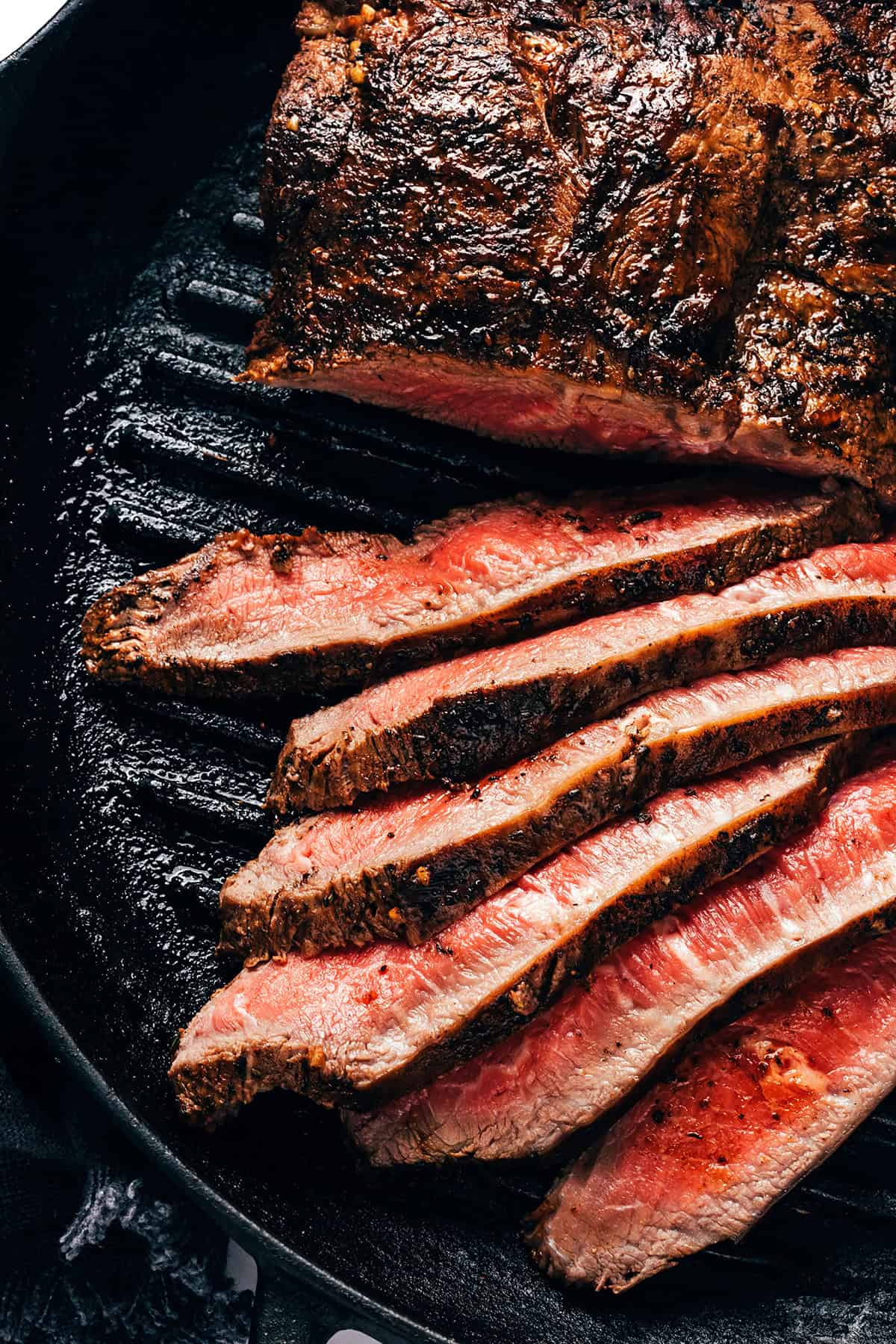 Juicy, tender flat iron steak sliced in a cast iron pan.