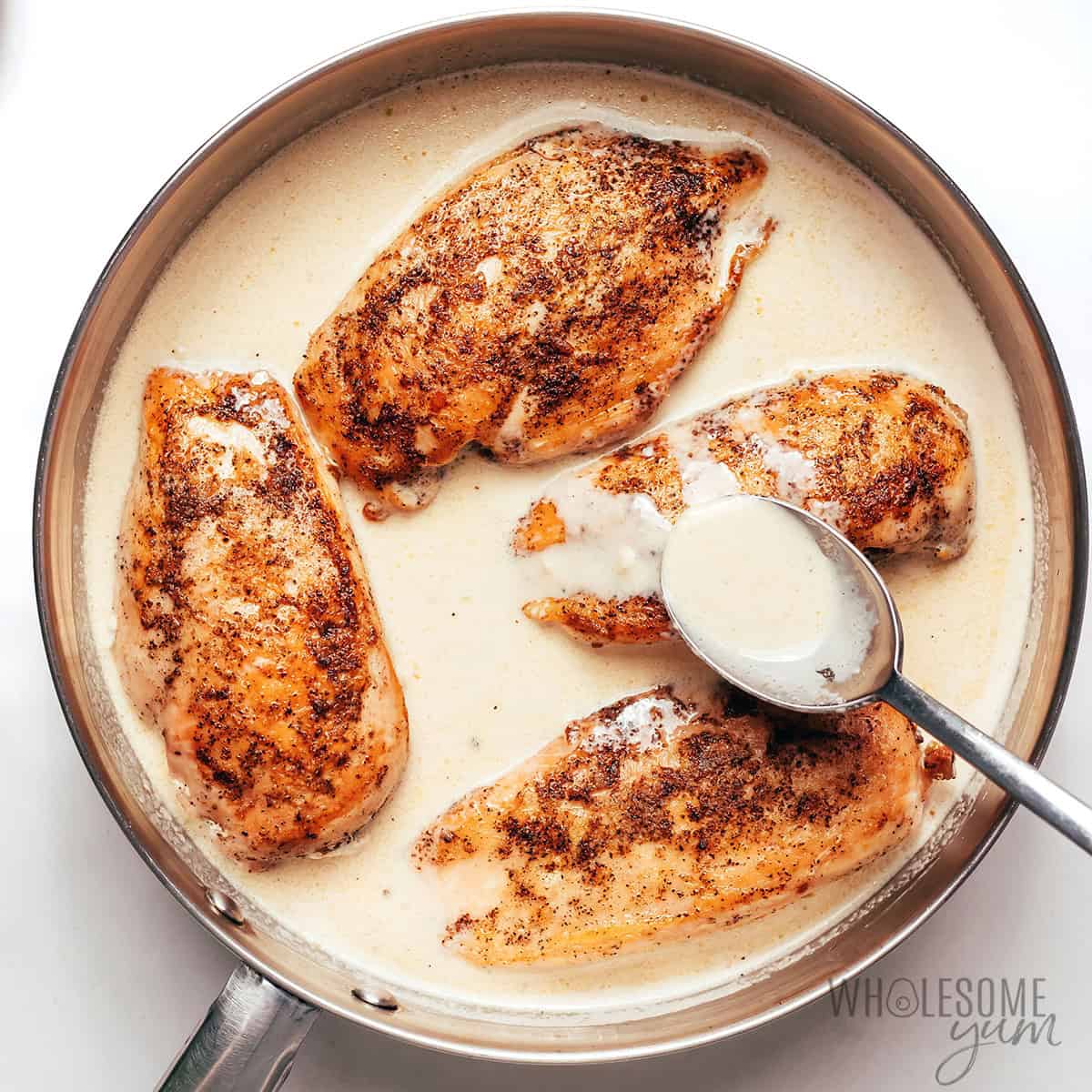 Spooning the pan sauce over the chicken.