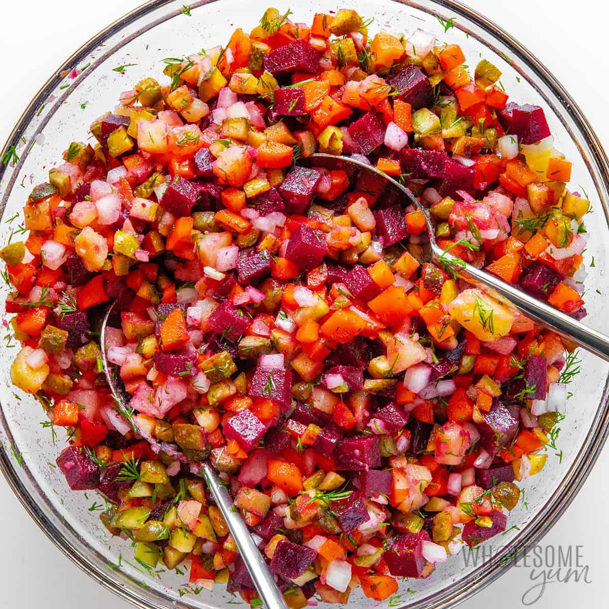 Russian beet salad mixed in a bowl with serving spoons.