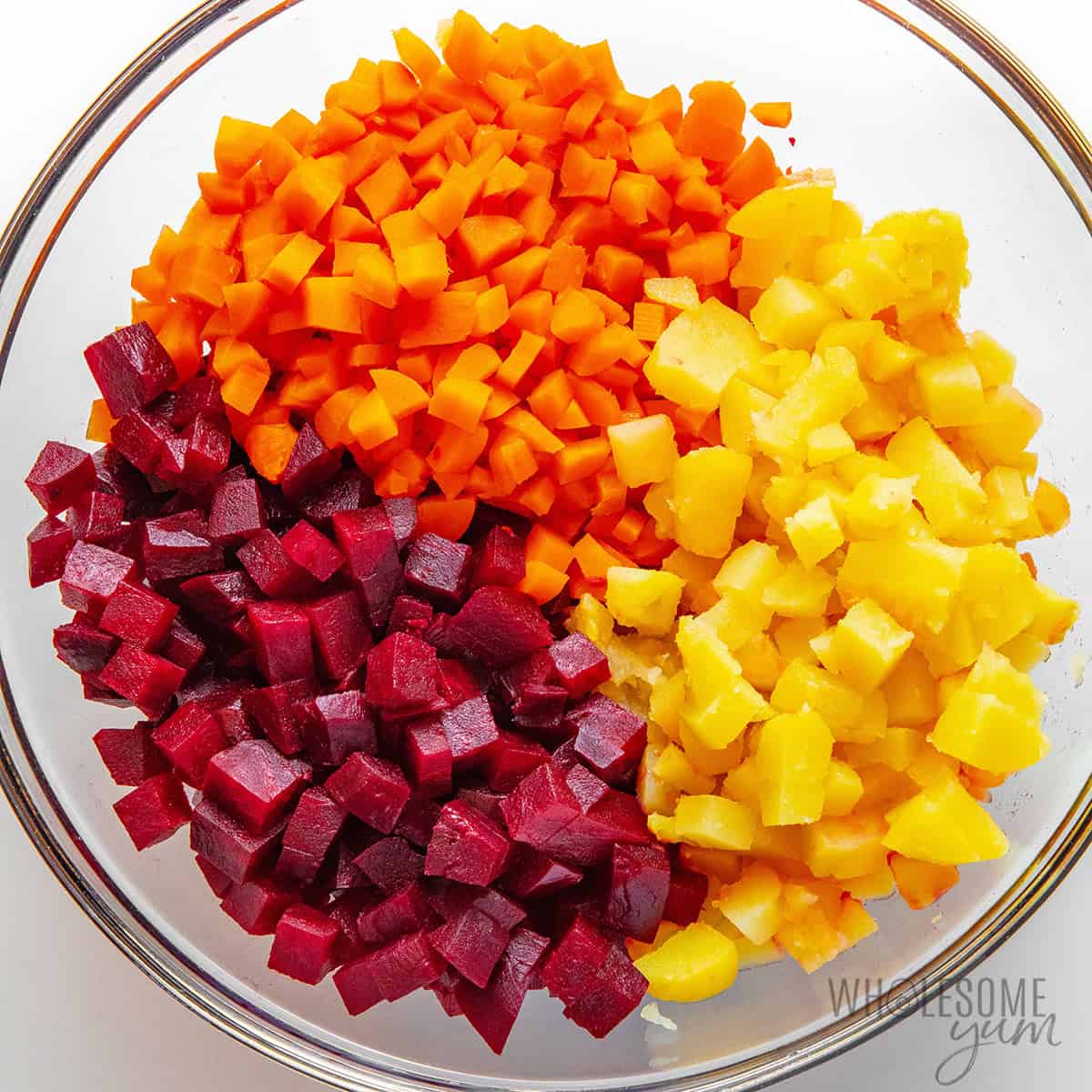 Beets, carrots, and potatoes diced into similar sizes and placed in a bowl.
