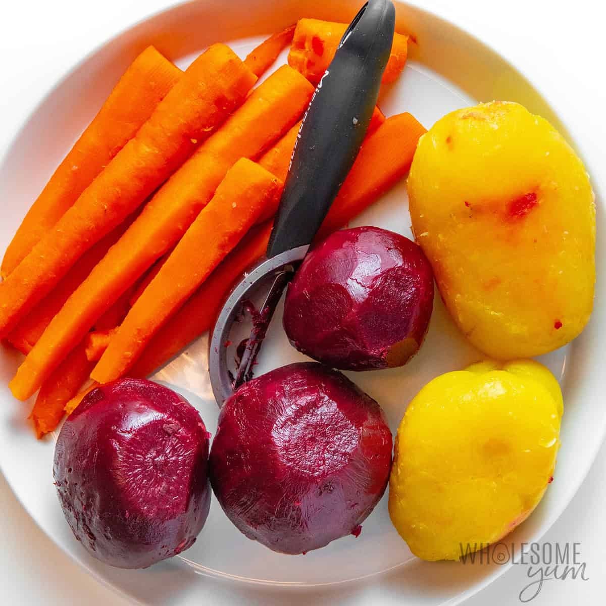 Peeled vegetables on a plate with a peeler.
