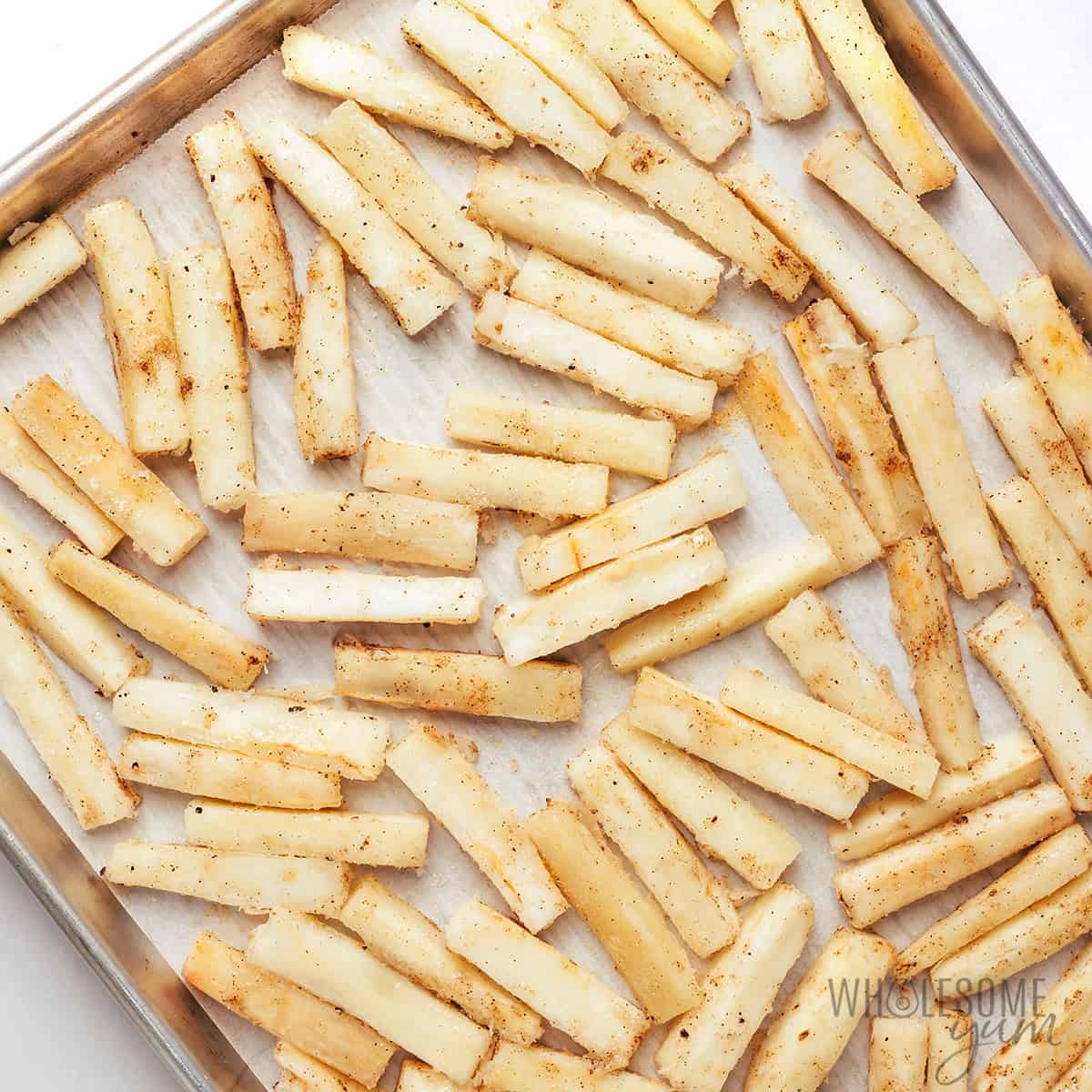 Fries spread out on a baking sheet in a single layer.