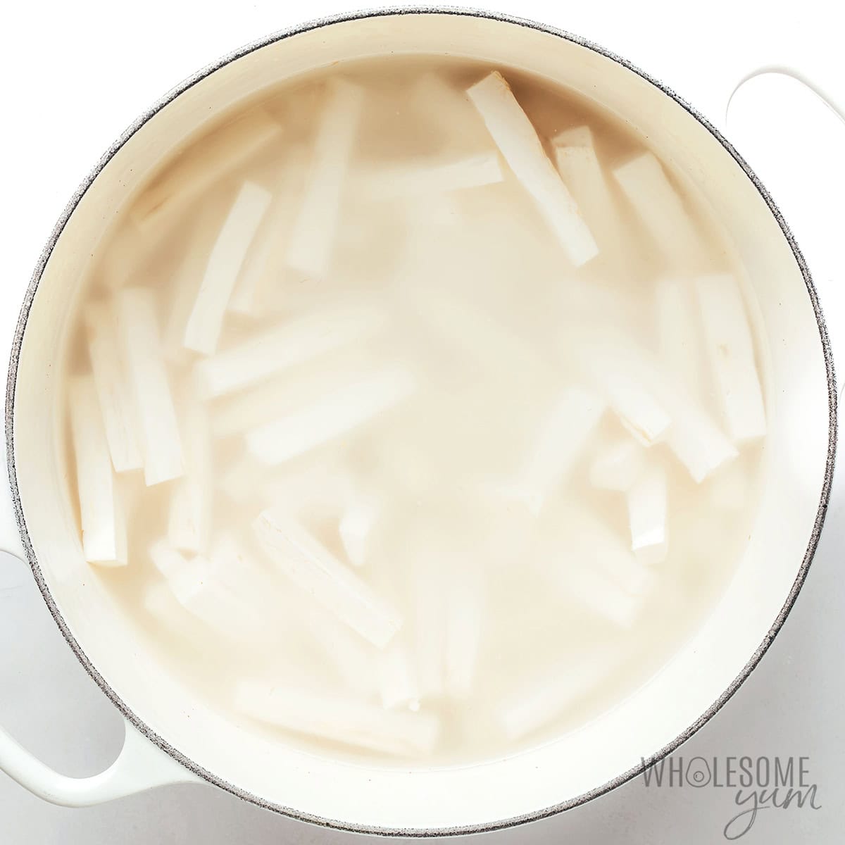 Boiling raw yuca fries in a large pot.