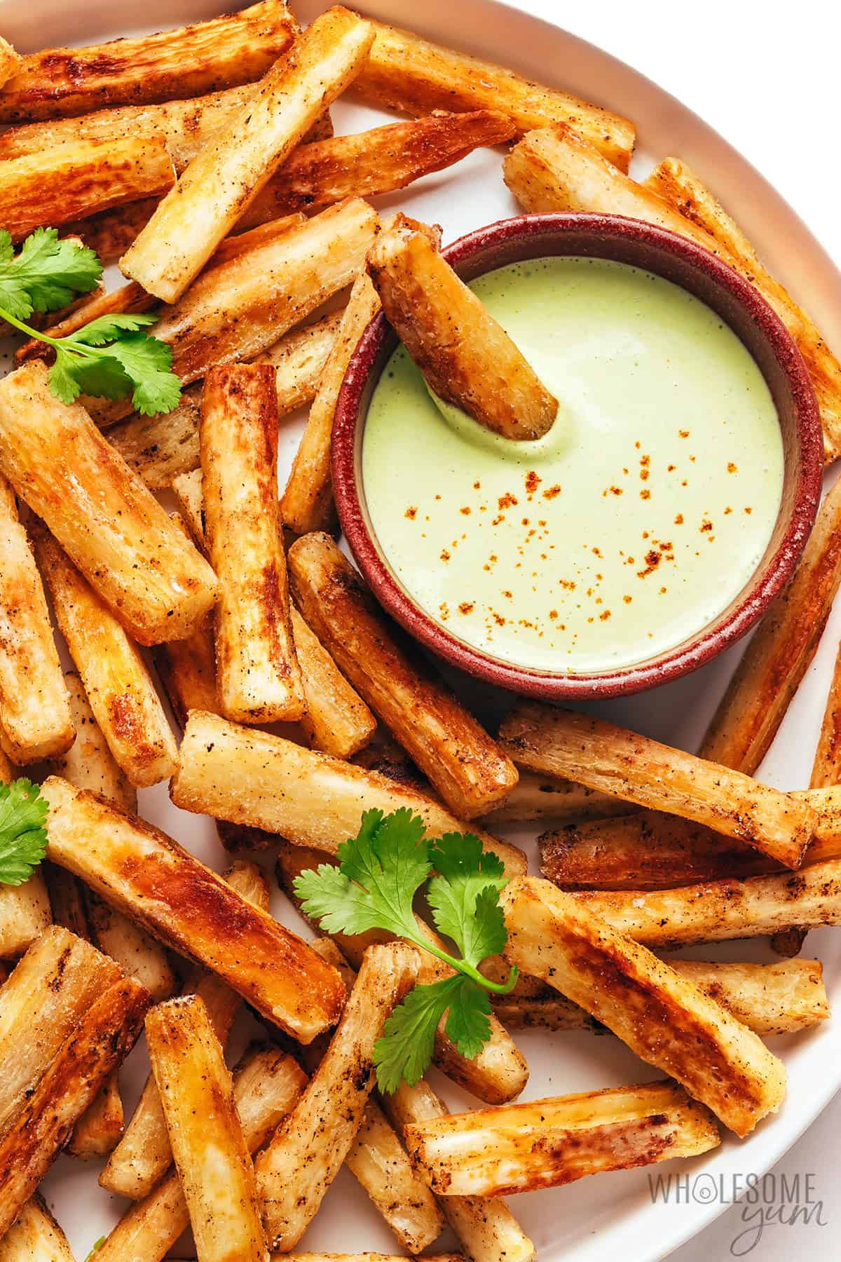 Golden, crispy fries on a plate with lime crema dip.