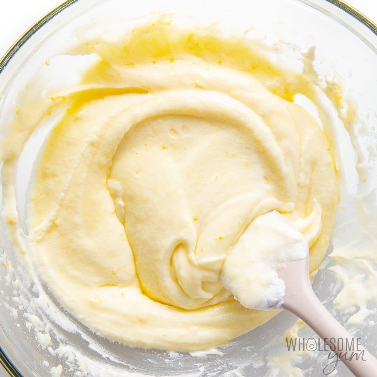 Folding lemon misture and heavy cream together in a bowl.